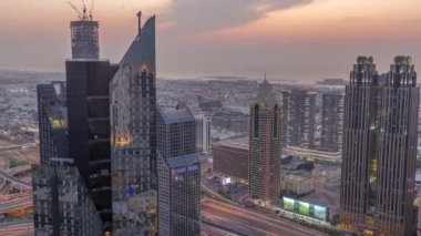 Dubai 'deki Sheikh Zayed Yolu' ndaki yüksek binalar. Gündüzden geceye geçiş zamanı, BAE. Uluslararası finans bölgesindeki gökdelenler. Arka planda evler ve villalar var.