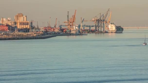 クレーンが付いている産業港のドッキングの間に容器の貨物船 輸出商業貿易ビジネスロジスティックと輸送 ポルトガルのリスボンでの夕日中のテジ川 — ストック動画