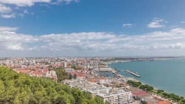 Panorama, Portekiz 'in Setubal şehrinde marina ve şehir merkezinin hava görüntülerini gösteriyor. Kırmızı çatılar ve kıyı şeridi yukarıdan gelen tekne ve gemilerle. Güneşli bir günde bulutlu bir gökyüzü