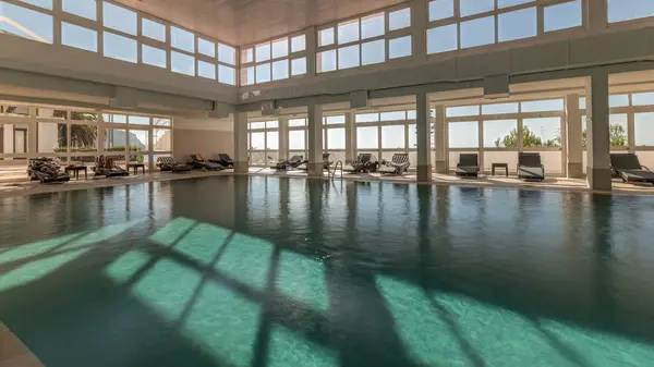 全景展示豪华室内游泳池 部分酒店温泉区的时间过去了 阳光透过大海的全景窗户和蓝天的云彩 — 图库照片