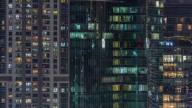 Ofis ve konutların pencereleri gece vakti aydınlatılıyor. Cam mimari, şirket binası, parlayan ışıklar.