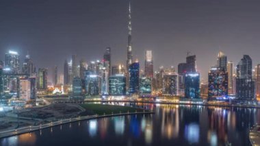 Tüm gece boyunca Dubai Business Bay ve Downtown 'ın havadan görüntüsü. Kanal boyunca çeşitli gökdelenler ve kuleler var. Vinçli inşaat alanı