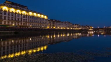 Ponte Alla Carraia 'nın alacakaranlık sahnesi ve gün batımından sonra sudaki yansımalarla Arno Nehri üzerinde gece gündüz tarihi binalar aydınlatmıştır. Floransa, Toskana, İtalya