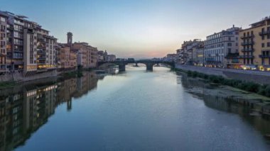 Ponte Santa Trinita Kutsal Üçleme Köprüsü 'nün alacakaranlık sahnesi. Gün batımından sonra Arno nehrinin üzerinde panoramik zaman geçişi. Suda yansımalar, eski evler. Floransa, İtalya