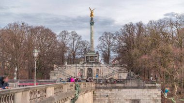Barış Sütunu 'nda altın Barış Meleği heykeli (Friedensengel) zaman aşımına uğramış insanlar, Isar nehri üzerindeki köprüde ip cambazı arıyorlar. Bavyera 'nın başkentinde halka açık bir park. Almanya, Münih, Bogenhausen
