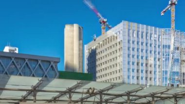 La Defence zaman atlaması panoraması, yüksek gökdelenlerin üzerinde vinçler bulunan iş ve finans bölgesi metro istasyonunun çıkışındaki binalar