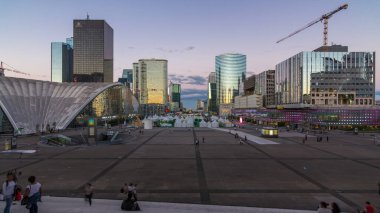 Günbatımından sonra gün batımından sonra gökdelenlerle dolup taşan çarpıcı Savunma Paris iş bölgesi. Ufukta görünen bir yay var..