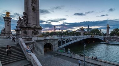 Paris 'teki Alexandre Köprüsü gece gündüz aydınlandı geçiş zamanı. Arka planda Grand Palais. Nehir kıyısı. Trafik sıkışık. Paris, Fransa