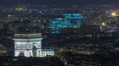 Aerial night timelapse view of Paris City and Triumphal Arch shot on the top of Eiffel Tower observation deck. Evening illumination from above clipart