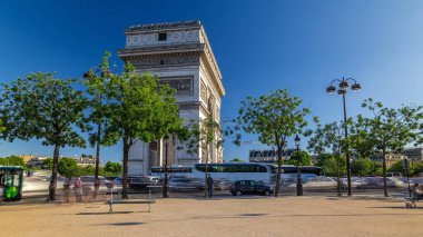 Arc de Triomphe zaman atlaması. Çevrede trafik ve ağaçlar var. Paris 'teki ünlü anıt Şanzelize' nin batı ucunda duruyor. Yazın mavi bulutlu gökyüzü