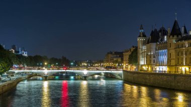 Conciergerie Castle ile Seine nehri üzerindeki kuleleri ve Pont au Change 'i örnek al. Gece aydınlatması suya yansıdı. Fransa, Paris