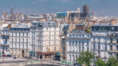 Arap Dünya Enstitüsü (Institut du Monde Arabe) binasının gözlem güvertesinden yola çıkan evler ve trafik ile Paris Panoraması. Üst hava manzarası. Yeşil ağaçlar ve mavi bulutlu gökyüzü. Fransa.