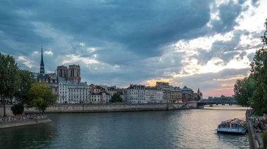 Notre Dame de Paris, Le Pont D 'Arcole köprüsü ile gün batımından geceye geçiş zamanı, Paris, Fransa, Avrupa. İnsanlar ve tekneler. Yaz gününün renkli gökyüzü Seine nehrinin yansımasıyla