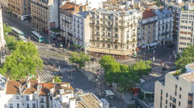 Paris 'teki evlerin çatılarının üstündeki hava gözlemi. Gün batımından önce kavşakta trafik ve kafede insanlar vardı.
