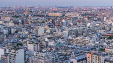 Paris 'teki evlerin çatılarının üstündeki hava panoraması gece gündüz geçiş zamanı. Günbatımından sonra aydınlanan kubbe ve diğer manzaralarla akşam manzarası