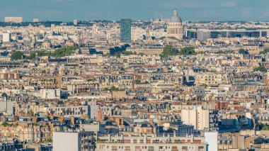 Paris 'teki evlerin çatılarının üstündeki hava manzarası. Güneş batmadan önce pantheon kubbesi ve gökdelenle akşam manzarası