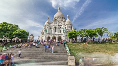 Tourists near the Basilica of the Sacred Heart of Paris (Sacra-Coeur) is a Roman Catholic church timelapse hyperlapse. Located at the summit of the butte Montmartre. Front view. Paris, France. clipart