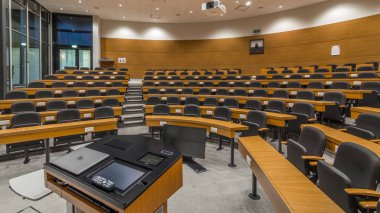 A wood paneled university lecture theatre or conference hall in business school timelapse. Laptop and remote control on the table clipart