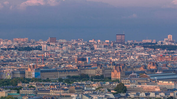 Aerial view of a large city skyline with Tuileries park at sunset with orange light timelapse. Top view from the Eiffel tower viewpoint. Paris, France.