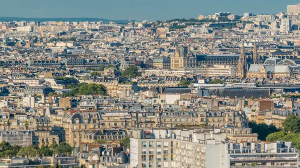 Paris 'teki evlerin çatılarının üstündeki hava manzarası. Müze, katedral kulesi ve gün batımından önce Fransız bayrağıyla akşam manzarası