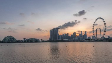 Singapur 'un merkezindeki ufuk çizgisi, doğudaki Garden' dan doğuya gece geçiş zamanına kadar izleniyor. Singapur. Aydınlatılmış gökdelenleri olan suda yansıma