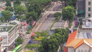 Traffic with cars on a street and urban scene in the central district of Singapore aerial timelapse. Hill street intersection. Green trees around clipart
