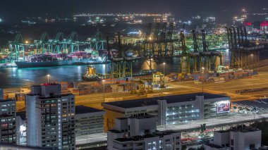 Singapur 'un ticari limanı gece vakti. Asya 'nın en işlek kargo limanının panoramik görüntüsü. Limanda ithalat ve ihracat malları yükleyen yüzlerce gemi ve binlerce konteynır var.
