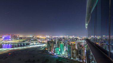 Abu Dabi şehir merkezindeki gökdelenlerle aydınlanan gökdelenler ve cam yüzeye yansıyan gökdelenler.