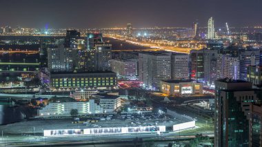 Abu Dabi şehir merkezinin gökyüzü çizgisi. Gece vakti gökdelenler aydınlatılmış ve yol trafiği var.