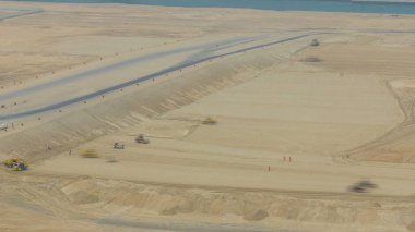 Yol yapımı sırasında toprak sıkıştırıcı ve buldozer zaman ayarlı çalışır. Yukarıdan hava görüntüsü. Abu Dabi, BAE