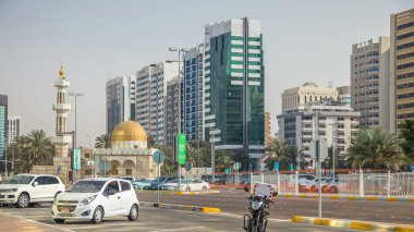 Corniche Bulvarı Sahil Parkı Abu Dabi timelapse Camii ve arka plan üzerinde gökdelenler ile kıyı şeridi boyunca. Bir tarafta avuç içi. Mavi gökyüzü güneşli gün