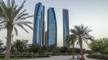 Ebu Dabi 'nin gökdelenleri Etihad Kuleleri' nin binalarıyla aydınlandı. Gece gündüz geçiş zamanları. Avuç içleri parka yakın. Birleşik Arap Emirlikleri