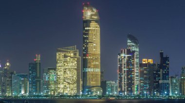 Abu Dabi Skyline 'ın panoramik görüntüsü ve gece vakti deniz manzarası, Birleşik Arap Emirlikleri. Aydınlatılmış gökdelenli Corniche manzarası