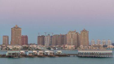 Katara Sahili 'nden gece gündüz görüntüsü. Gün batımından sonra Doha, Katar' da İnci 'ye geçiş zamanı. Yerleşim binaları ufuk çizgisi