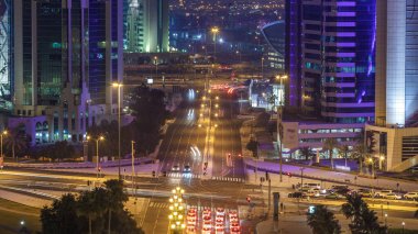 Katar, Doha Timelapse 'da West Bay yolunda trafik var. Aydınlatılmış modern gökdelenler ve gece çatıdan kesişen hava manzarası.