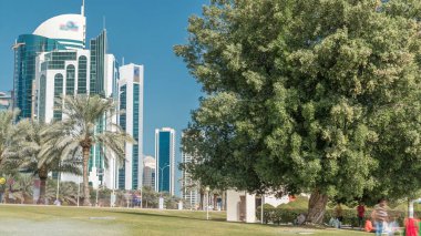 Batı Körfezi 'ndeki Doha' s Corniche 'de modern gökdelenler ve ağaçlarla, Katar. Corniche, fantastik gezinti yerleri, su sporları, geleneksel dhow yarışları ve daha pek çok şeyle bilinen popüler bir egzersiz mekanıdır.