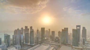 Günbatımında gökdelenler başkent Katar 'ın ticaret merkezi Doha' nın ufuk çizgisinde. Sisli havada hava manzarası. Bulutlu turuncu gökyüzü
