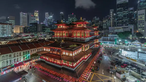 シンガポール中華街では夜間のタイムラプスに仏歯遺跡寺院があり 街のスカイラインを背景にしています 高層ビルや塔が建ち並ぶ — ストック写真