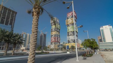 Katar 'ın başkenti Lusail' de bulunan renkli Al Marina İkiz Kuleleri binasıyla Doha Skyline zaman çizgisi aşırı hızlanması. Palmiyeler ve ağaçlar. Yolda trafik vardı.