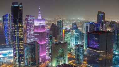 Katar 'ın Doha Zaman Çizelgesi' nde Batı Körfezi bölgesinin ufuk çizgisi. Aydınlatılmış modern gökdelenler geceleri çatıdan gökyüzü manzarası. Yolda trafik vardı.