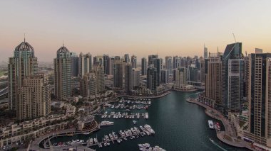 Dubai yat limanı panoraması, gece gündüz tekne ve yat panoraması, geçiş zamanı, aydınlatma ışıkları kapalı, BAE. Gökdelenleri ve kuleleri olan gökyüzü manzarası