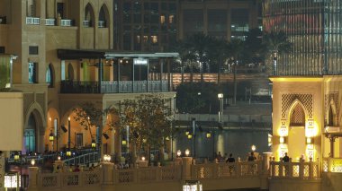 Dubai 'nin en büyük müzik çeşmesinin yakınındaki yürüyen insanlarla aydınlatılmış köprü, BAE zaman ayarlı..