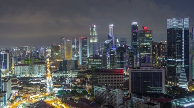 Çin Mahallesi ve Singapur Şehir Merkezi 'nin çatıdan gece geçiş zamanlarını gösteren hava manzarası. Yol trafiğiyle aydınlanan modern kuleler ve gökdelenler