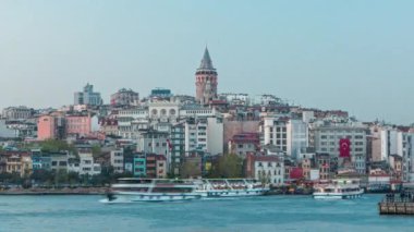 Evening view over golden horn bay on the galata tower and its neighborhood day to night transition timelapse in Istanbul. Illuminated city skyline reflected on water with ship at spring day