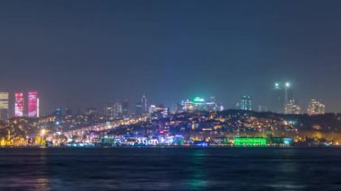 Night timelapse view of besiktas district with some illuminated skyscrapers in Istanbul taken from asian part of the city. Reflection on Bosphorus water