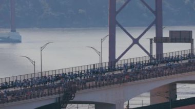 Lizbon 'da koşmak 25 Nisan köprüsünü yukarıdan Tagus nehri hava manzarası üzerinden geçmek demek. Büyük bir kalabalık baştan sona köprüden aşağı ilerliyor. Su arka planda akar