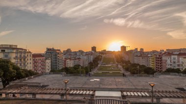 Panorama Alameda Dom Afonso Henriques 'deki çimlerin üzerinde gün batımını renkli binalar ve Aydınlık Çeşme hava saatleriyle gösteriyor. Lizbon, Portekiz 'de akşam gökyüzü ile yukarıdan görünüm