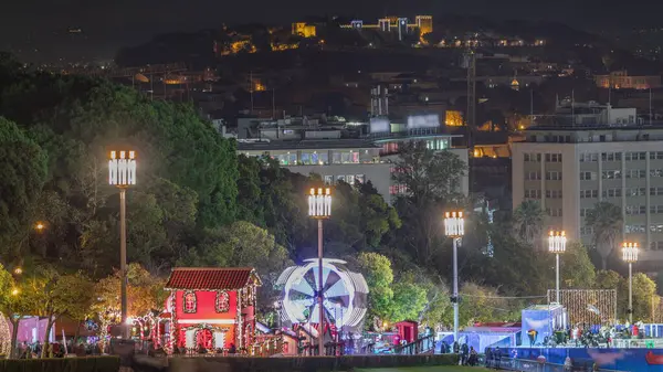 stock image Market inside the traditional Christmas event at Parque Eduardo VII timelapse in the city of Lisbon in Portugal. People ice skating near Ferris wheel. View from above with castle on the top