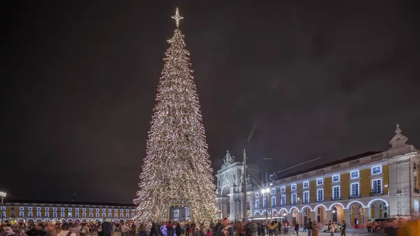 Panorama showing Commerce square illuminated and decorated at Christmas time in Lisbon night timelapse. Commercio square with Christmas tree and people tourists crowd around. Holiday times. Portugal