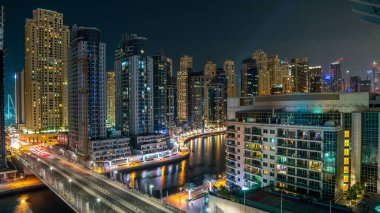 Dubai Marina 'nın gece görüş açısının en üstünde. Suda hafif tekne izleri ve yolda arabalar var. Dubai, BAE. Çatıdan hava görüntüsü